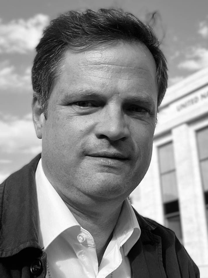 Portrait en noir et blanc de Michael McCain devant le bâtiment des Nations Unies.