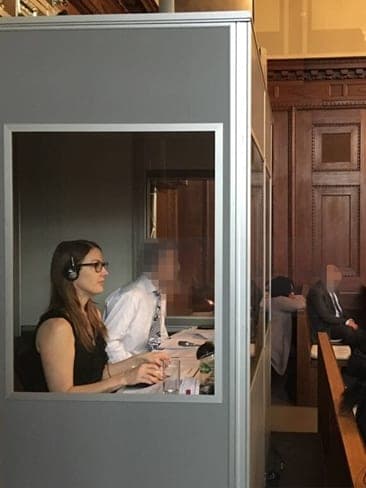Viviane Murray McCain en cabine d'interprétation, casque sur les oreilles, lors d'une audience dans une salle lambrissée.